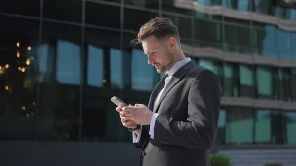 Κομψό Όμορφος Επιχειρηματίας Κρατώντας Τηλέφωνο Ανάγνωση Ηλεκτρονικού Ταχυδρομείου Στέκεται Στο — Αρχείο Βίντεο