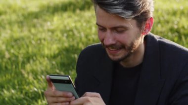 İş adamlarının iyimser videosu akıllı telefonuyla mesajlaşan kurumsal uygulama grubunu açık havada tutuyor. Takım elbiseli komik adam kahkaha telefonu. Yüksek kalite 4k görüntü