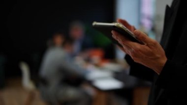 İş adamının tablet kullanırken yakın plan fotoğrafı. Adam iş görüşmesindeki tutarlılıklar hakkında yeni verileri inceliyor. Bilgi aramak için modern akıllı telefon dinleme ekranını tutan eller. Yüksek kalite 4k