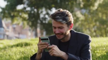 Mutlu öğrenci, yeni telefon cihazını doğada kullanıyor. Açık havada 