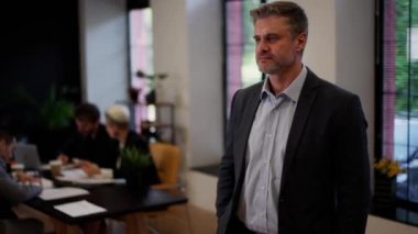 Kendine güvenen iş adamı gülümseyen takım elbisesini takım konferansında giyer. Uluslararası şirketin başarılı adam şefi. Yönetim kurulunun mali müdürü. Yüksek kalite 4k görüntü