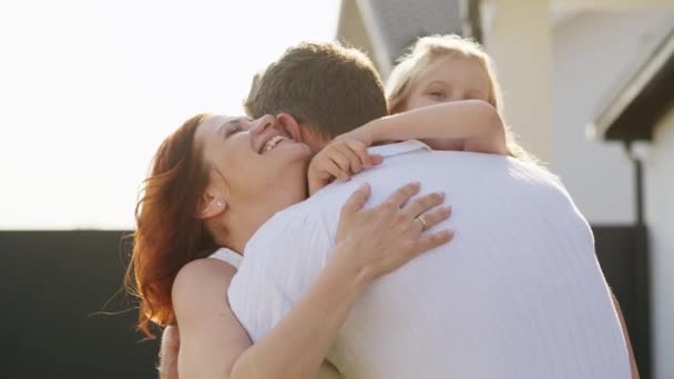 美国梦之家就在他们的房子附近 一个男人抱着他的女儿 娶了妻子 母亲和女儿拥抱和亲吻 心里充满柔情和温暖 — 图库视频影像