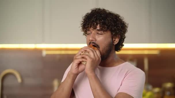 ファーストフード配送のコンセプト ビッグバーガーを持っている陽気な男は オークシンボルを示して彼のクールな味を承認します ビッグハンバーガーを食べる若者は 良いフィードバックをする 自宅でチートミール 高品質4Kについて — ストック動画
