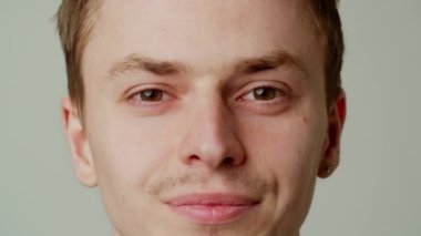 Güzel gülüşlü bir erkek model bir diş macunu reklamı için poz veriyor. Genç bir adam stüdyodaki aktörler veritabanı portföyü için fotoğraf çekiyor. Kameraya bakar. Kapatın. Yüksek kalite 4k görüntü