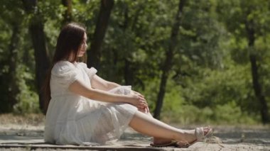 Pozitif duyguları olan güzel bir kız yaz ormanında kumların üzerinde yan oturup meditasyon yapar. Beyaz elbiseli bir bayan, şakacı ve cilveli bir şekilde saçlarını düzleştiriyor. Genç bir kadın poz verir.