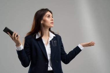 Genç işveren kız vergileri saymak için yeni uygulamaları kopyalıyor. İş kadını omuz silkiyor ve meraklı görünüyor. Kadın akıllı telefon kullanırken kablosuz bağlantı arıyor. Kadın girişimcinin ikilemi