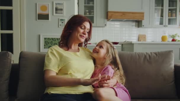 Een Vriendelijke Glimlachende Moeder Zit Bank Kamer Met Haar Dochter — Stockvideo