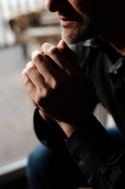 Kapalı kollu silueti yakın çekim gölgede Tanrı 'yla konuşurken. Erkek el ele verip çeneye dokunur ve af diler. Yetişkin baba evliliğini kurtarmak için kaderine yalvarıyor. Yüksek kalite fotoğraf