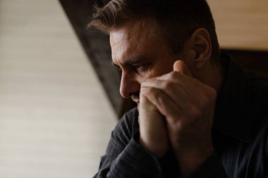 Depresyon kavramı. Yetişkin bir adam kollarını sıktı ve dini düşündü. Genç erkek duası zihinleriyle el ele tutuşmuş. Dindar adam günahları için yalvarır. Düşünceli bir insan. Yüksek