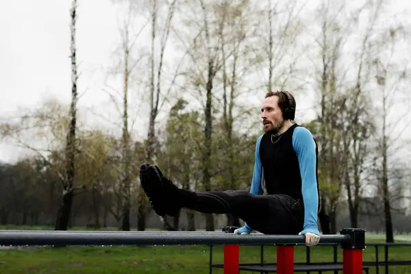 Parkta karın kasları olan bir sporcu. Profesyonel sporcu vücudunu maratona hazırlıyor. Erkek jimnastikçi, karın kaslarını paralel parmaklıklar kullanarak çalıştırıyor. Yüksek kalite fotoğraf