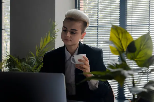 Genç beyaz iş kadını iş sonuçlarını kontrol etmek için dizüstü bilgisayar kullanıyor. Not defterindeki sosyal medyada gezinirken kahve içen bir kadın. Ofis müdürü kız işyerinde dinleniyor. Yüksek kalite fotoğraf