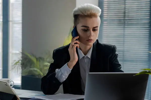 年轻的女商人打电话给她的同事解决电脑问题 股市经纪人电话交谈 女商人为讲客户话的智能手机推广新产品 正规部门的妇女 — 图库照片