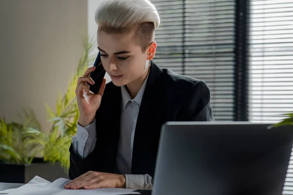 Confident businesswoman calling support service with a smartphone to fix contract issues. Attractive caucasian business lady phone talking her assistant when found mistake in documents. Woman checking