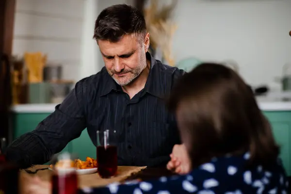 Adult man praying before food with family at the dining table. Jewish parent blessed during having a meal. Religious holiday. Spiritual union with god. Lunch thanksgiving. High quality photo