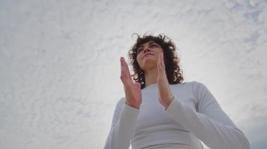 Kıvırcık saçlı, nefes egzersizi yapan spor kadınının alt görüntüsü. Kadın yoga eğitmeni, yeni eğitim almış. Kız açık havada namaste antrenmanı yapıyor. Yüksek kalite 4k görüntü
