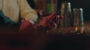 Bir adamın kafeteryadaki akıllı telefondan internete göz attığı yakın çekim. Erkek telefon kullanıyor ve gece kulübünde içki siparişini bekliyor. Lokantanın içinde el şaklatan aletler. Hafta sonu akşamı dinlenme. Yüksek