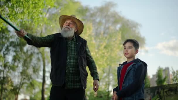 Älterer Kaukasischer Mann Der Mit Seinem Enkel Fischt Und Das — Stockvideo
