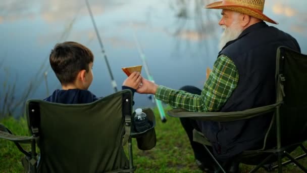 家庭钓鱼的后视镜 祖父在户外给孙子吃三明治 老渔夫在森林自然环境中与孙子孙女共进午餐 高质量4K — 图库视频影像