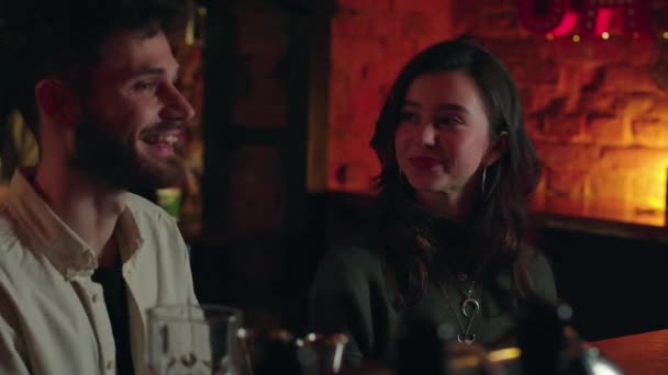 美しいカップルは 新しいバーでお互いに話し合っています 彼らは笑顔で アルコールを飲んでいる ビールパブで注文する若い学生 夏の夜の楽しみについて 高品質の4K映像 — ストック動画
