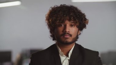 Takım elbiseli Hintli bir işadamının görüntüsü. Genç, gülümseyen bir işadamı bulanık bir ofisin önünde duruyor. Yüksek kalite 4k görüntü