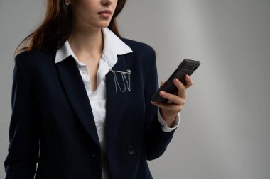 Ciddi bir iş kadını telefonla resmi spor ceket giyiyor. Sosyal medyayı kontrol etmek için elinde akıllı telefon tutan bir kadın. Cihazlar için mola zamanı. İnternette boş zaman sörfü. Yüksek kalite fotoğraf