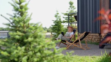 Orta yaşlı bir kadın yaz tatilini kır evinde geçiriyor, işten sonra bahçeye çıkıp dinleniyor, ağaçlarla çevrili sakin bir çevrede bir koltukta oturuyor. Bir bayan.