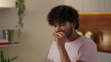 Kahvaltı kavramı. Genç adam lezzetli tost yiyor ve bir fincan kahve içiyor. Adam evde çayla sağlıksız ekmek sandviçi yiyor. Rahatlamış öğrenci öğle yemeği yiyor. Yüksek kalite 4k görüntü