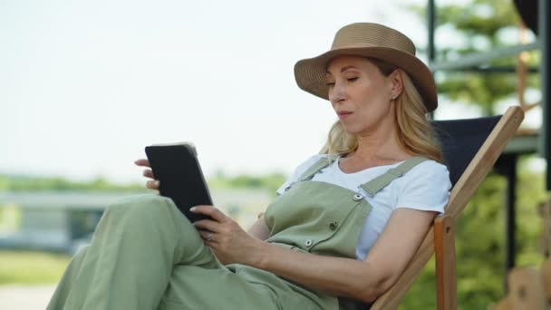 여성은 시골에서 휴가를 보내고 야외에서 즐기며 정원에서 휴식을 취하며 의자에 — 비디오