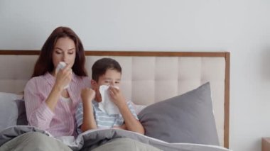 Hasta anne ve oğlu yatak odasındaki kanepede uzanıp burunlarını sümükten peçetelere silip el sallıyorlar. Anne ve çocuk grip ya da soğuk algınlığına yakalandılar, evde tedavi uygulayın.