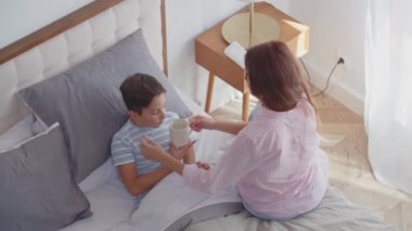 Hasta bir çocuk kendini iyi hissetmez, fincandan sıcak tıbbi çay içer, yatak odasına uzanır ve yatak istirahatı sağlar. İlgili genç bir anne yanında oturur, oğluna bir fincan antipirretik şurup ya da içecek verir,