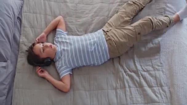 Ein Glücklicher Junge Schlafzimmer Springt Imposant Auf Das Bett Liegt — Stockvideo