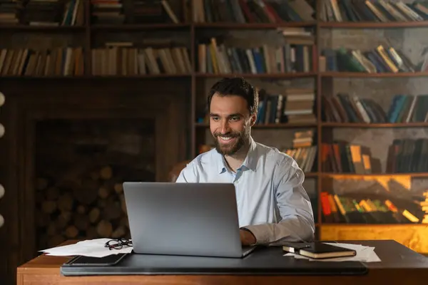 Gülümseyen Bir Adam Kütüphanedeki Bir Masada Oturur Bir Dizüstü Bilgisayar — Stok fotoğraf