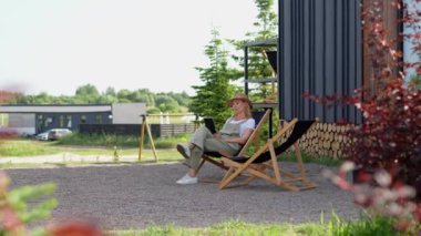 Orta yaşlı bir kadın yaz tatilini kır evinde geçiriyor, işten sonra bahçeye çıkıp dinleniyor, ağaçlarla çevrili sakin bir çevrede bir koltukta oturuyor. Bir bayan.