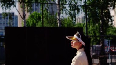 Genç bir sporcu kız rakiplerine servis yaptığı için topu fırlatıyor ve tenis maçında raketle vuruyor. Bir bayan sporcu uluslararası müsabakalara hazırlanıyor ya da