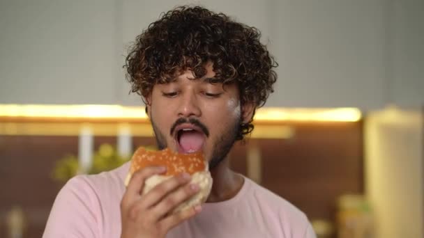 미국식 패스트 푸드의 배고픈 사람은 거대한 햄버거를 즐거움 젊은이는 집에서 — 비디오