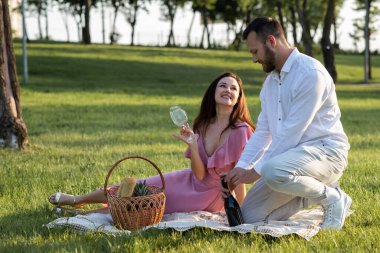 Erkek arkadaşın piknikte şampanya şişesini açtı. Adam dışarıda güzel bir kız arkadaş için romantik bir randevu hazırlıyor. Kocasının alkol açmasını bekleyen çekici bir kız. Romantik aile yemeği. Yüksek