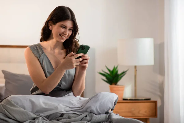 Glimlachend Meisje Zit Bed Met Smartphone Ochtend Gelukkige Jonge Vrouw — Stockfoto
