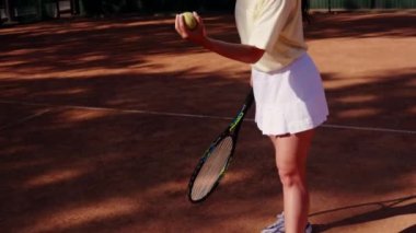 Genç bir sporcu kız topu yere atar ve servis yapmadan önce topu avucunun içine alır. Sporcu bir kadın tenis maçında raketle grev yapıyor. Ağır çekim modu. Yüksek kalite 4k