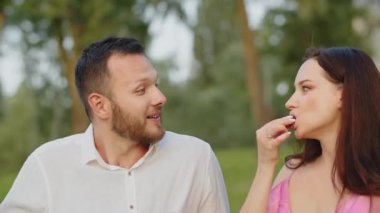 Piknikte üzüm yiyen ve öpüşen genç bir çifti vurdular. Şirin bir eş, kocasını tatlı bir üzümle besledikten sonra öper. Dışarıda romantik bir yemek yiyen güzel bir aile. Yüksek kalite 4k