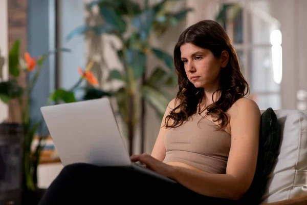 自宅でラップトップを使ったフリーランサーガール ブルネットの若い女性がコンピュータのキーボードに入力します ホームコンセプトの仕事 高品質の写真 — ストック写真