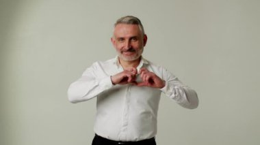 Sana saygı gösteren, orta yaşlı bir patron. Beyaz gömlekli, olgun bir iş adamı. Gri arka planda kalbi olan. Tecrübeli maço sevgi gösterisi. Yüksek