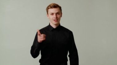Siyah gömlekli mutlu genç adam kameraya doğru işaret ediyor. İyi iş, harikasın. İşadamı sana işaret parmağıyla iltifat ediyor. İnsanlar için en iyi motivasyon. Yüksek kalite 4k