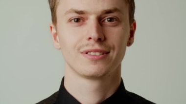 Gri renkli arka planda tek başına duran başarılı genç işadamının gülümsemesi. Siyah gömlekli neşeli adam memnun. Tamam, başardın. Patron seni onaylıyor. Dişlek gülümsemeli sevgili.