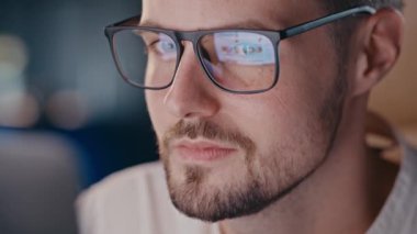 Genç adam gözlük yansıtmalı ekrana bakıyor. Web tasarımcısı hisse senedi resimlerine göz atıyordu. Gözlüklü, sosyal ağlarda gezinen konsantre bir adam. Yüksek kalite 4k görüntü