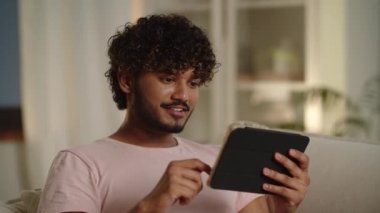 Uzaktan görüşmede erkek arkadaşın güler. Tablet bilgisayarı olan genç adam kanepede yatıyor. Adam dokunmatik ekrana bakıyor ve internette iletişim kuruyor. İnternette bilgi araştırması yapan erkek öğrenci