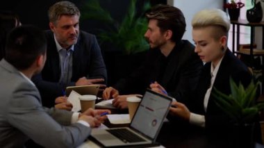 Takım oluşturan patron tablet notlarına bakıp hisse fiyatlarının nasıl yükseldiğini anlatıyor. Meslektaşlar ofiste tartışır. İşadamı çalışanları dinliyor. Yüksek kalite 4k görüntü