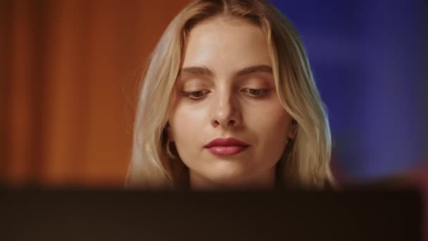 一个年轻漂亮的金发姑娘 带着自信和傲慢的目光看着电脑显示器或笔记本电脑的屏幕 一位漂亮的女商人以感情来公正地传达和阅读信息 — 图库视频影像