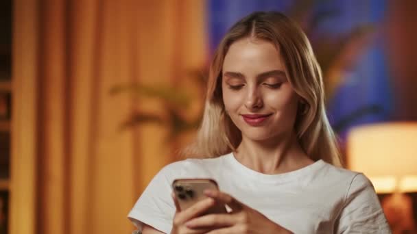 Una Guapa Rubia Sonriente Usa Teléfono Inteligente Disfruta Leyendo Historias — Vídeo de stock