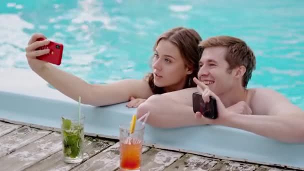 年轻漂亮的夫妇在度假时拍照 两个情人在游泳池里自作主张 男友和女朋友在度假胜地拍蜜月照 高质量的4K镜头 — 图库视频影像