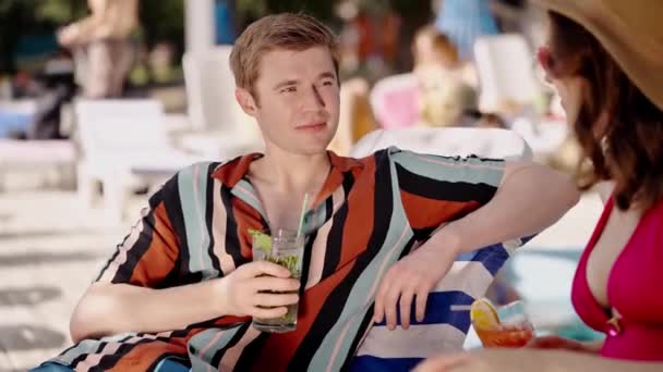 快乐的年轻人喝酒 讲述工作中的一些故事 躺在日光浴床上的情侣们 在温暖的天气里喝着冷冰冰的鸡尾酒 家庭在海滩度假 他们尝试新的Mojito混合 — 图库视频影像